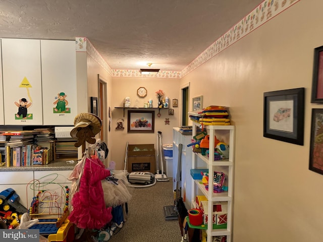 recreation room featuring a textured ceiling and carpet flooring