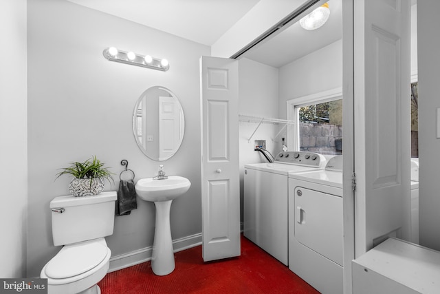 bathroom with washing machine and dryer, toilet, and sink