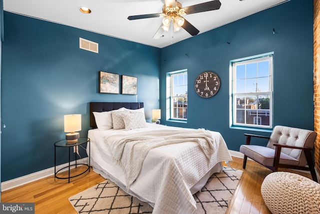 bedroom featuring light hardwood / wood-style floors, multiple windows, and ceiling fan