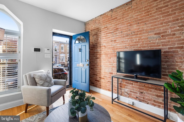 living room with hardwood / wood-style floors and brick wall