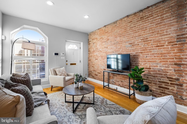 living room with wood-type flooring and brick wall