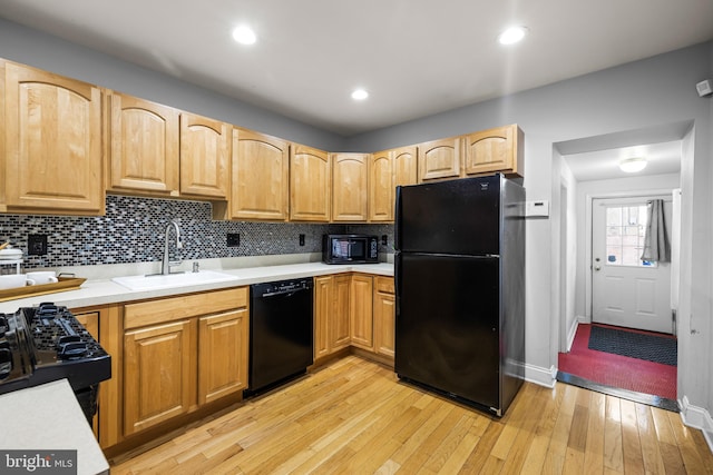 kitchen featuring light hardwood / wood-style floors, black appliances, sink, and tasteful backsplash