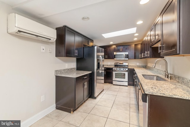 kitchen with an AC wall unit, light tile patterned flooring, appliances with stainless steel finishes, sink, and a skylight