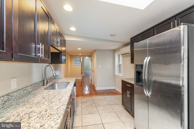 kitchen featuring a wall unit AC, sink, light stone countertops, light hardwood / wood-style flooring, and stainless steel fridge