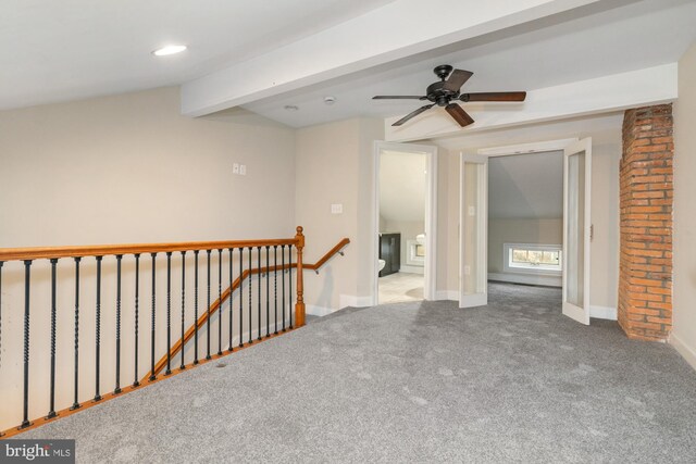 carpeted spare room featuring ceiling fan and beamed ceiling