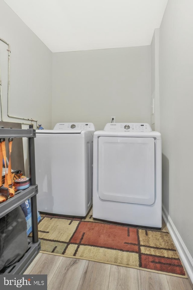 clothes washing area featuring independent washer and dryer and light hardwood / wood-style flooring