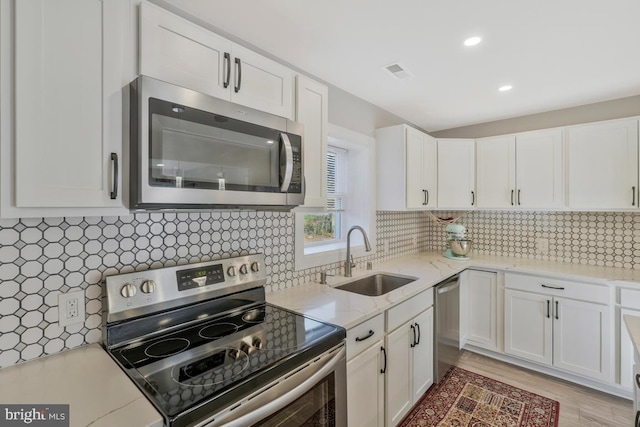 kitchen featuring decorative backsplash, sink, white cabinets, and appliances with stainless steel finishes