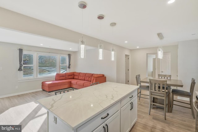 kitchen with light hardwood / wood-style flooring, white cabinets, decorative light fixtures, and a kitchen island