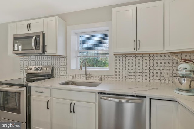 kitchen featuring stainless steel appliances, white cabinetry, tasteful backsplash, and sink