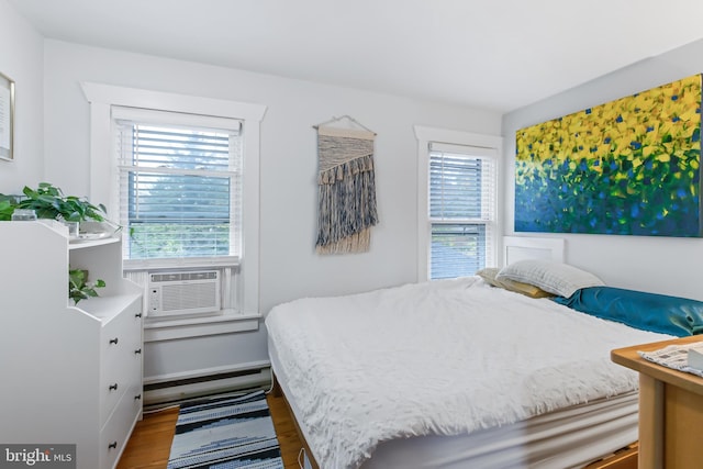 bedroom featuring hardwood / wood-style flooring, cooling unit, and baseboard heating