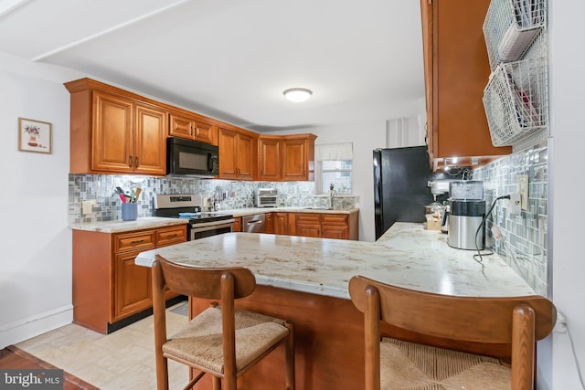 kitchen with black appliances, a kitchen bar, sink, decorative backsplash, and kitchen peninsula