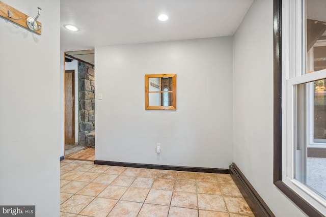 empty room featuring baseboard heating, light tile patterned floors, and plenty of natural light