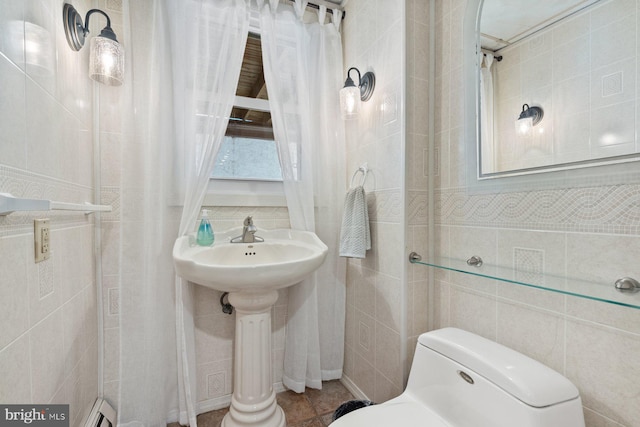 bathroom featuring toilet, a shower with curtain, and tile walls