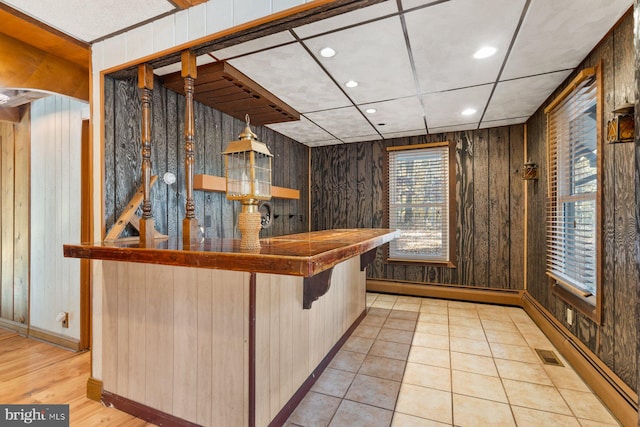 bar with light hardwood / wood-style floors, wood walls, and baseboard heating