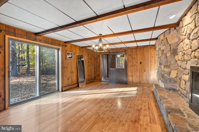 unfurnished living room with light hardwood / wood-style floors, baseboard heating, beamed ceiling, and wooden walls