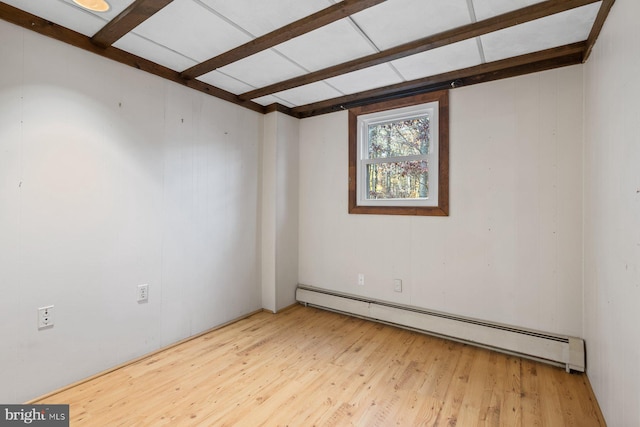 empty room featuring a baseboard heating unit, wood-type flooring, and wood walls