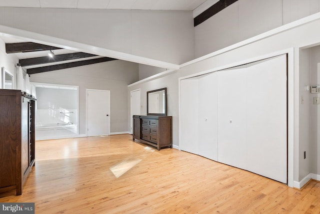 unfurnished living room featuring lofted ceiling with beams and light wood-type flooring