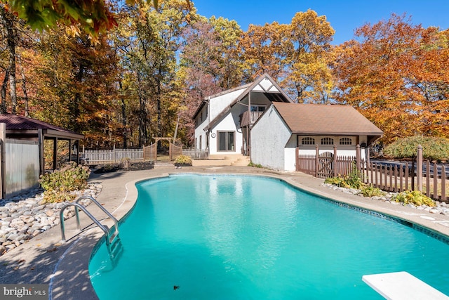 view of swimming pool featuring a diving board and a patio