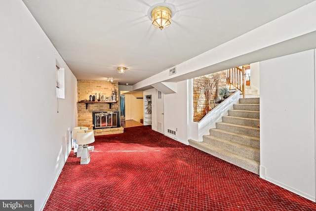 basement featuring carpet floors, a brick fireplace, and brick wall