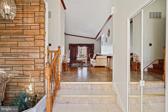 entryway with a chandelier, high vaulted ceiling, and ornamental molding