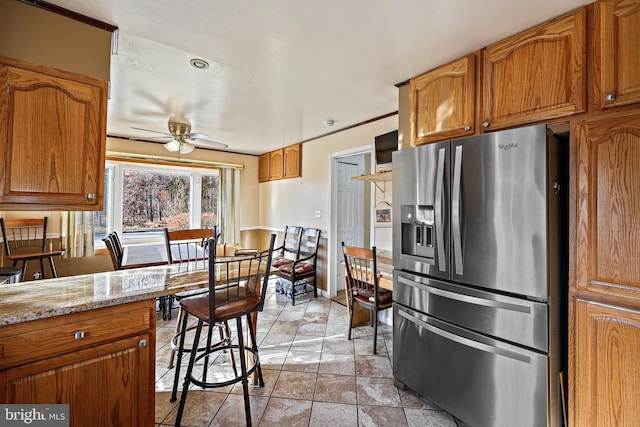 kitchen with light stone countertops, stainless steel refrigerator with ice dispenser, and ceiling fan