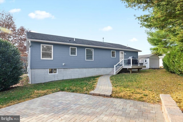 rear view of house with a deck, a patio, and a yard