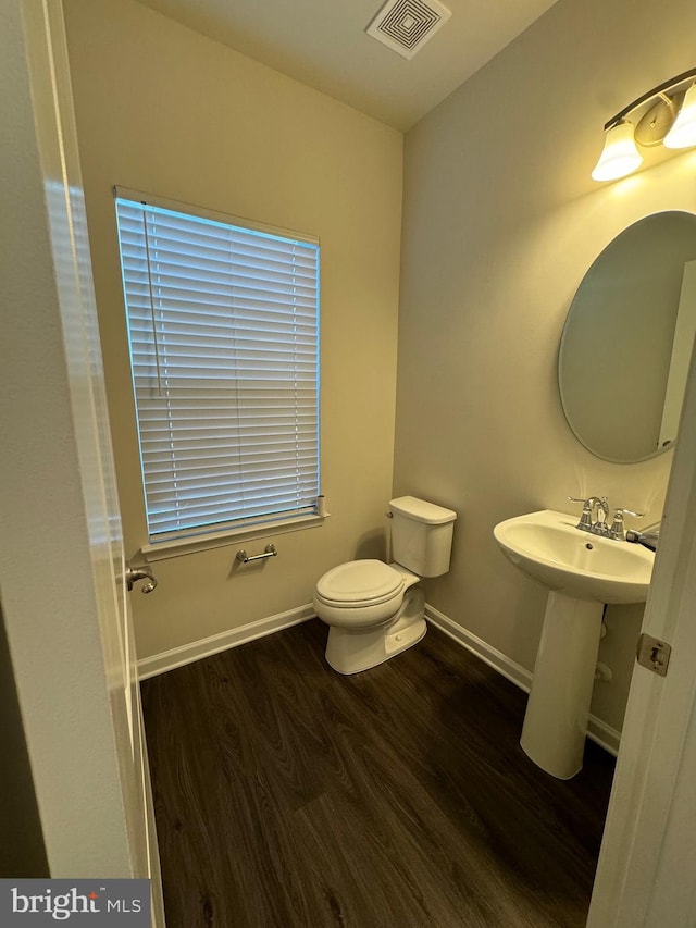 half bath with wood finished floors, baseboards, and toilet