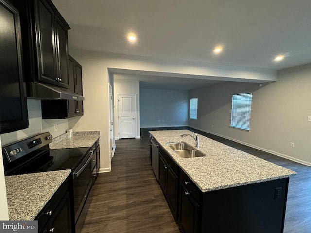 kitchen featuring light stone countertops, appliances with stainless steel finishes, dark wood-type flooring, sink, and a center island with sink