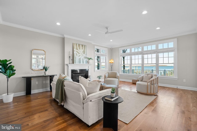 living room with crown molding, a water view, dark hardwood / wood-style floors, and ceiling fan