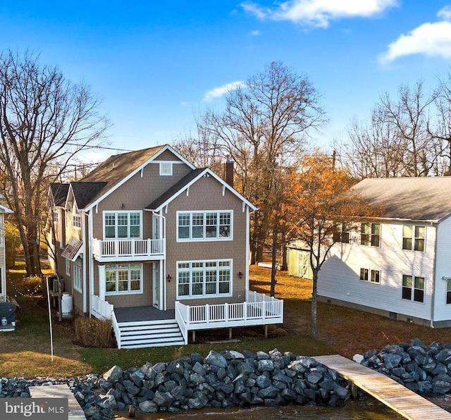 back of house featuring a storage unit, a balcony, and a wooden deck