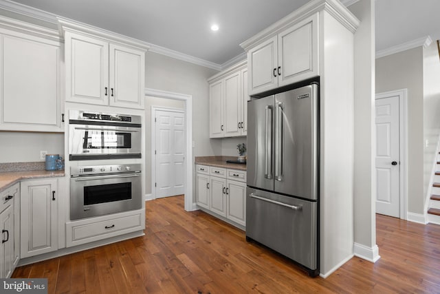 kitchen featuring white cabinetry, dark hardwood / wood-style flooring, crown molding, and appliances with stainless steel finishes