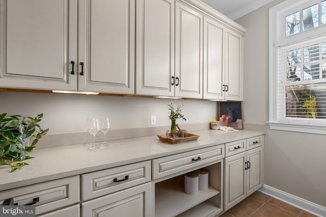 interior space with dark tile patterned flooring, white cabinets, and ornamental molding