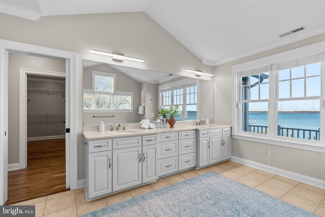 bathroom featuring vanity, a water view, crown molding, vaulted ceiling, and tile patterned flooring