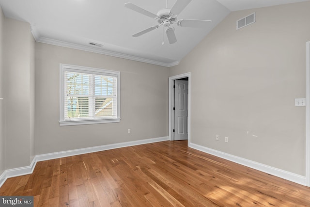 empty room featuring hardwood / wood-style flooring, ceiling fan, crown molding, and vaulted ceiling