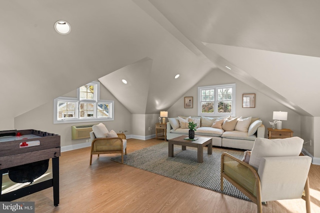 living room with an AC wall unit, light hardwood / wood-style floors, and vaulted ceiling