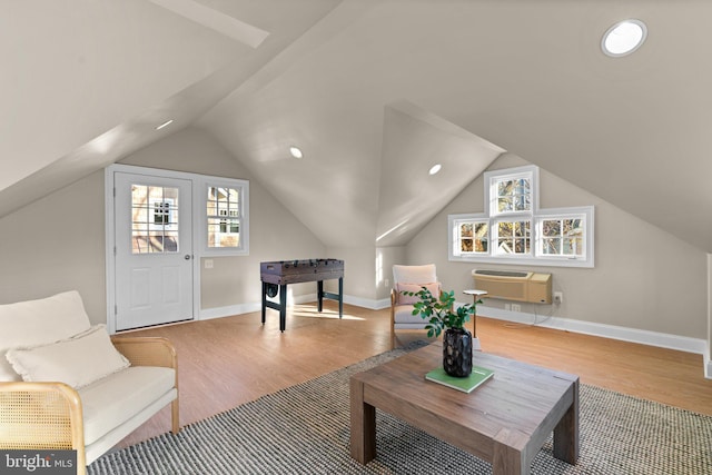 living area featuring a wealth of natural light, vaulted ceiling, light hardwood / wood-style flooring, and a wall mounted AC