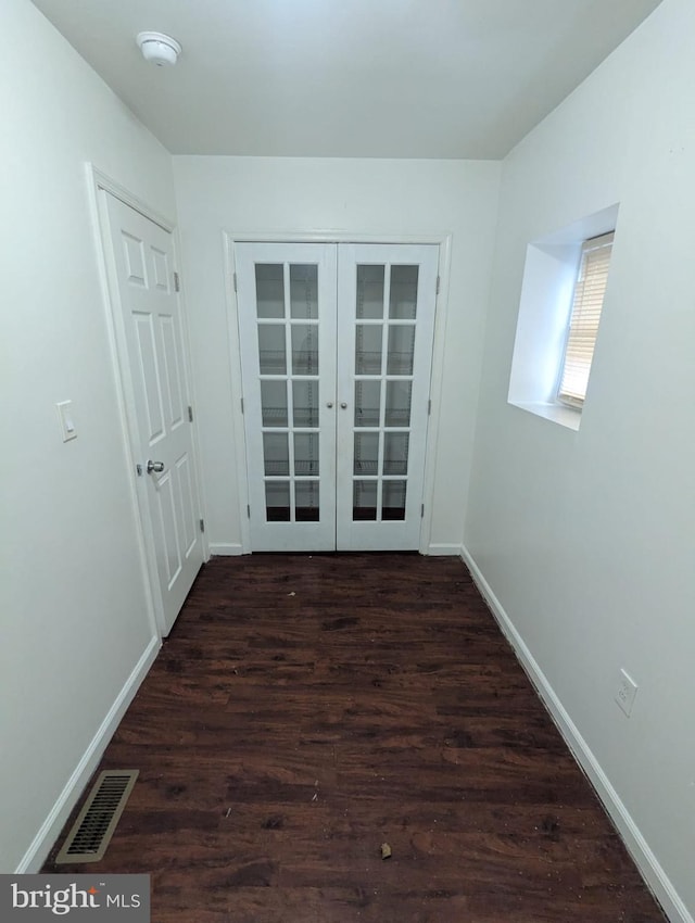 empty room with dark wood-type flooring, french doors, visible vents, and baseboards