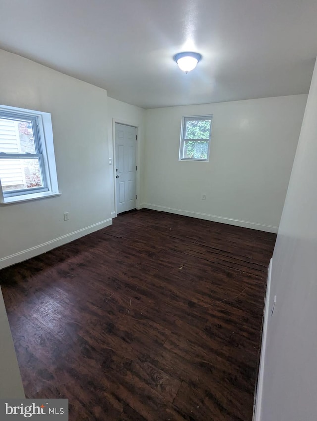 empty room with dark wood-style flooring and baseboards