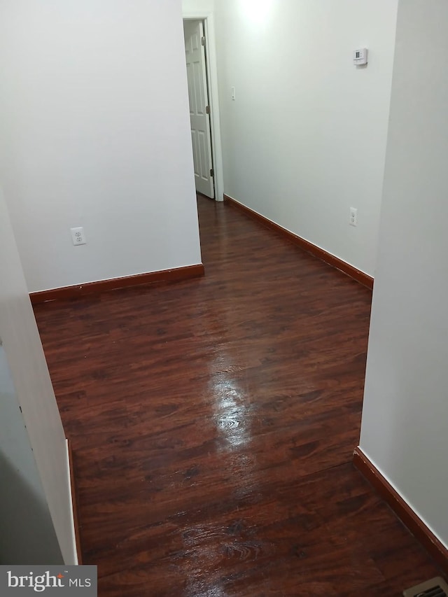 empty room with baseboards and dark wood-style flooring