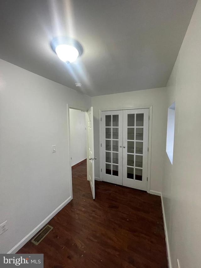 unfurnished room with baseboards, visible vents, dark wood-type flooring, and french doors