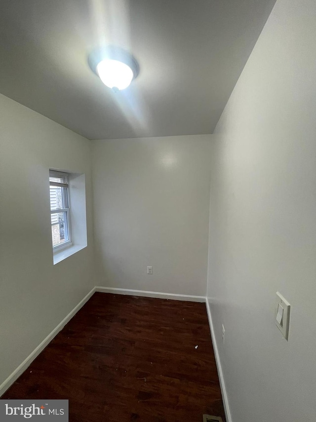 empty room featuring dark wood-style flooring and baseboards