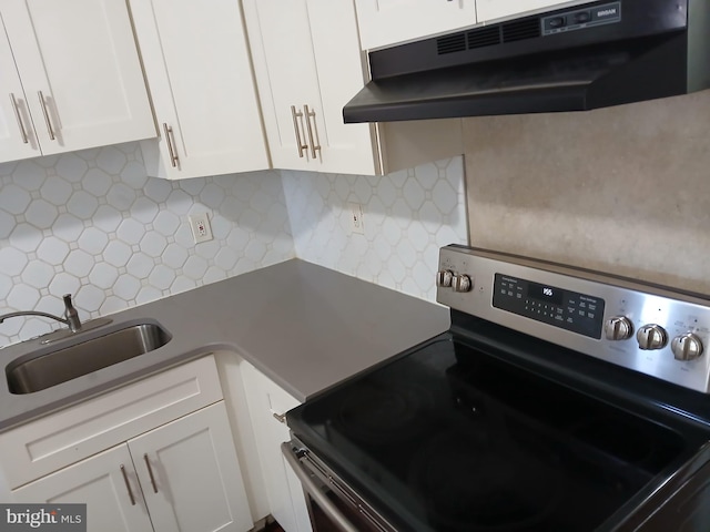 kitchen featuring white cabinets, stainless steel electric range oven, a sink, under cabinet range hood, and backsplash