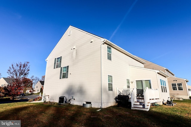 rear view of house featuring a lawn, a wooden deck, and central AC