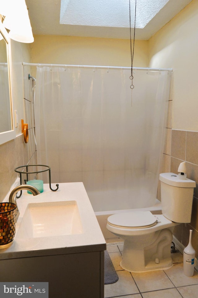 full bathroom featuring tile patterned floors, toilet, vanity, tile walls, and a textured ceiling