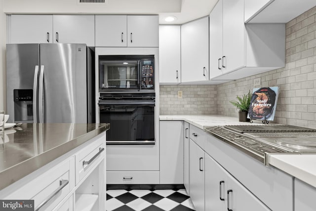 kitchen featuring tasteful backsplash, white cabinets, and black appliances