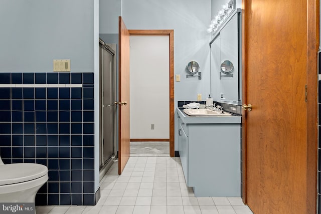 bathroom featuring vanity, a shower with door, tile patterned floors, and tile walls