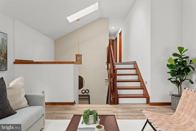 living room featuring vaulted ceiling with skylight and light hardwood / wood-style floors