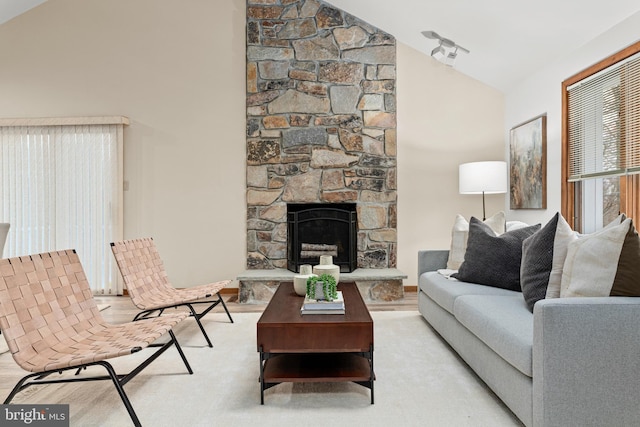 living room with high vaulted ceiling and a stone fireplace