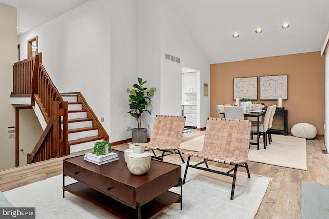 living room featuring light wood-type flooring and high vaulted ceiling