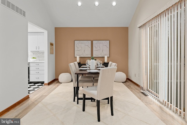 dining space featuring vaulted ceiling and light wood-type flooring